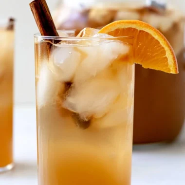 A refreshing fall harvest punch served in a glass with seasonal fruit decor.