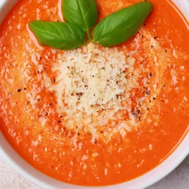 Bowl of high protein tomato soup garnished with fresh herbs