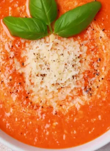 Bowl of high protein tomato soup garnished with fresh herbs