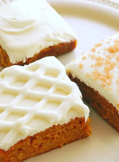 Delicious pumpkin bars with cream cheese frosting on a serving plate.