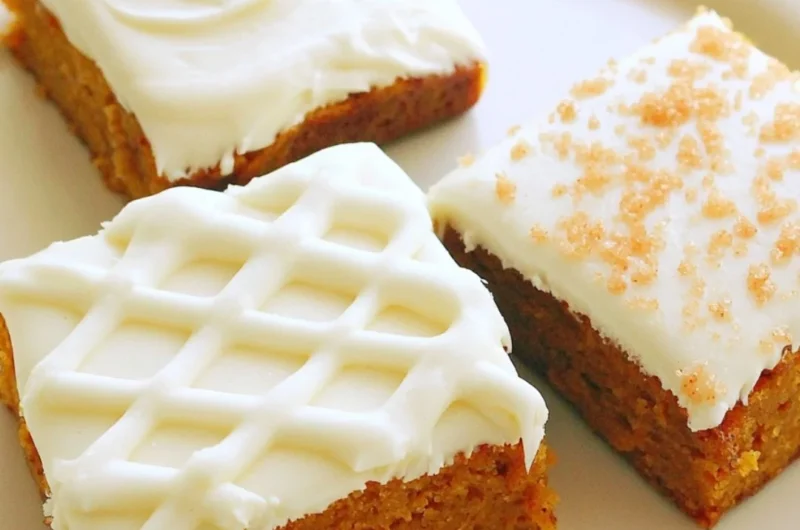Delicious pumpkin bars with cream cheese frosting on a serving plate.