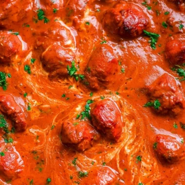 A bowl of cozy Chicken Tikka Masala with rice and fresh herbs