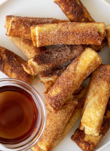 Delicious French Toast Roll-Ups served with syrup and berries on a plate