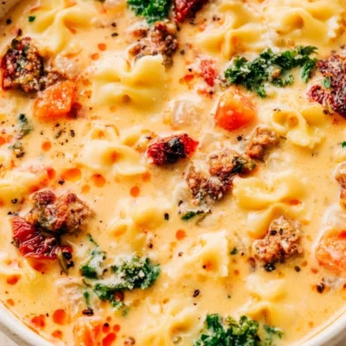 Bowl of warm Italian sausage pasta soup served with fresh herbs and crusty bread.