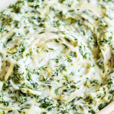 Creamy spinach dip served in a bowl with fresh vegetables and chips