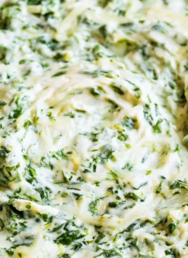 Creamy spinach dip served in a bowl with fresh vegetables and chips