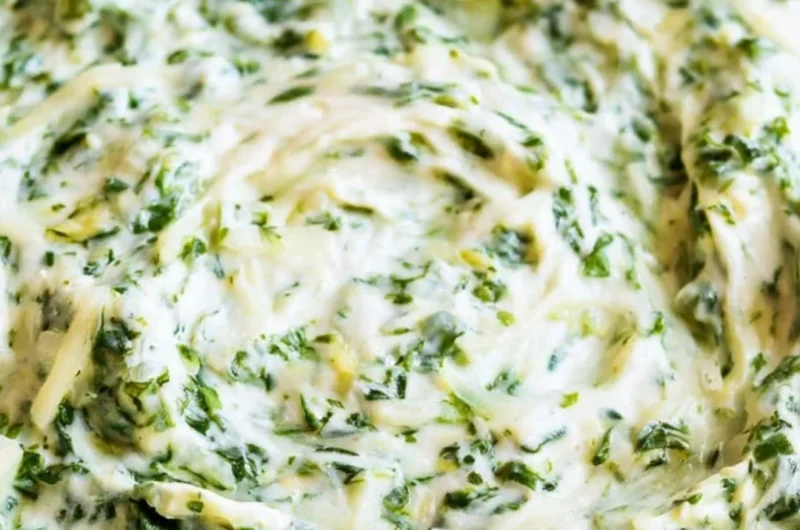 Creamy spinach dip served in a bowl with fresh vegetables and chips