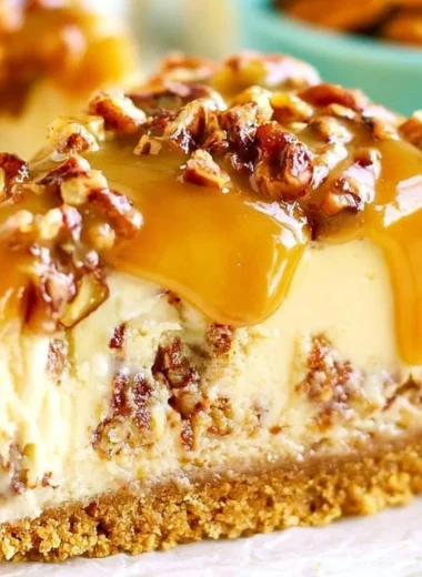 Slice of decadent Pecan Praline Cheesecake topped with nuts and caramel drizzle.