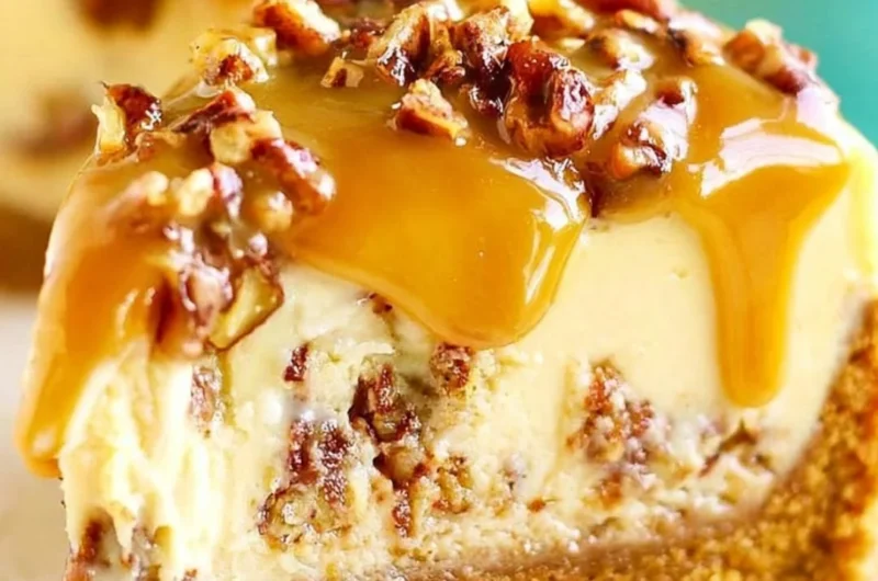 Slice of decadent Pecan Praline Cheesecake topped with nuts and caramel drizzle.