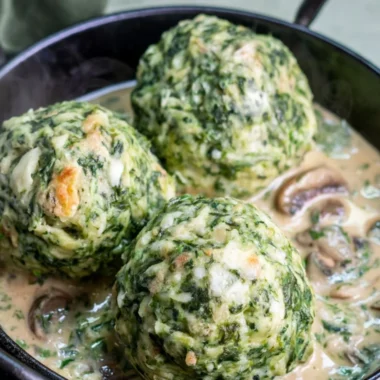Plate of spinach dumplings topped with savory mushroom sauce